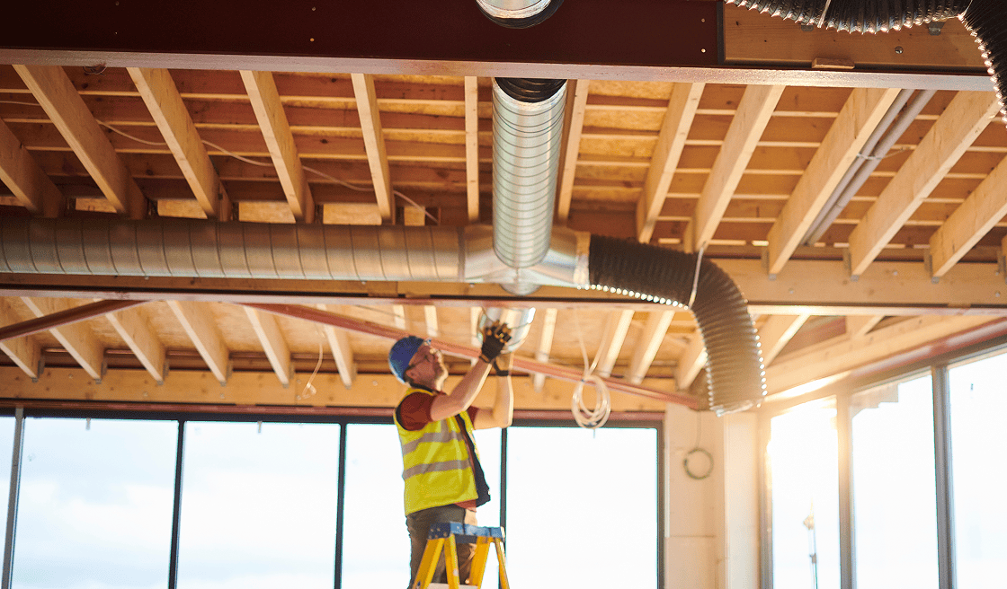 Man on ladder fixing ductwork